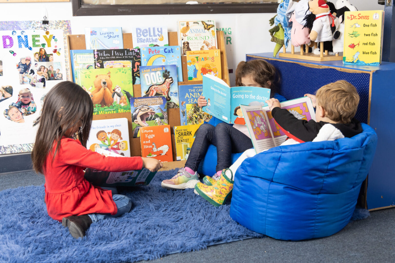 Two children reading books in a cozy classroom corner.